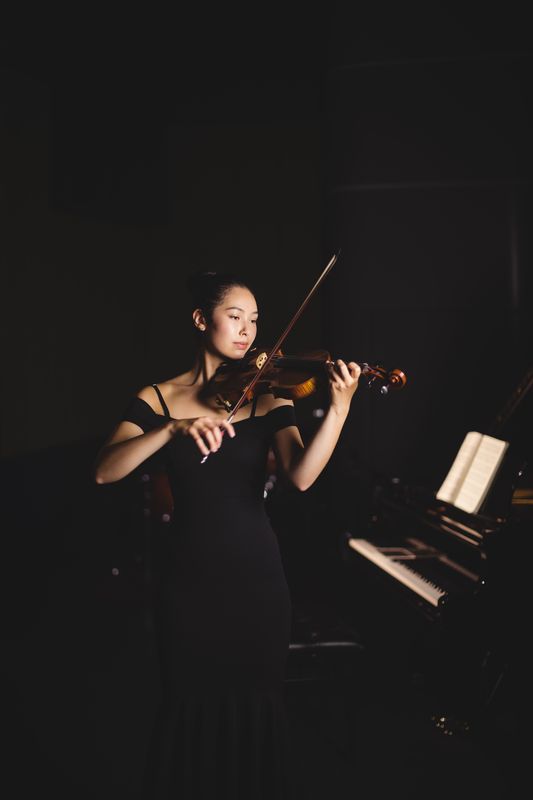 Female student playing violin in a studio